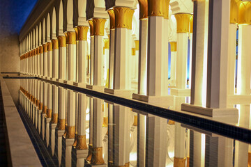 Obraz premium Perspective View Of Illuminated Mosque Columns Reflected In Water Pool At Night
