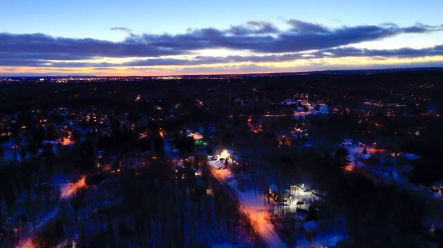 Aerial winter night view of Saint Jerome Quebec with snowy houses and glowing streets at blue hour. g.