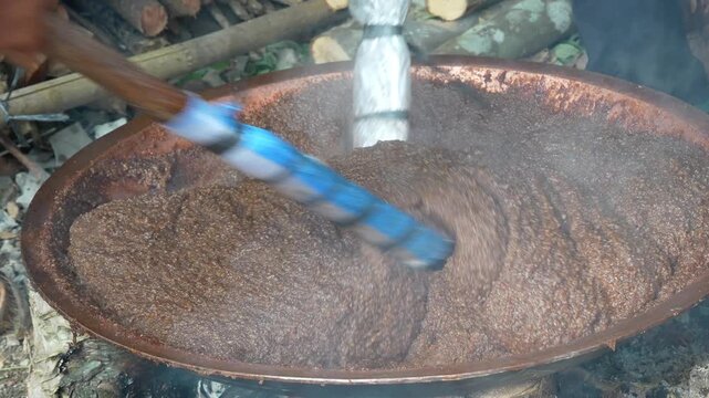 Traditional Indonesian dodol cooking in a large wok over an open fire, authentic cultural culinary heritage and process.