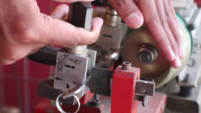 Locksmith in workshop makes new key. Professional key making in locksmith. Person who makes and repairs keys and locks. Key maker Machine and Accessory.