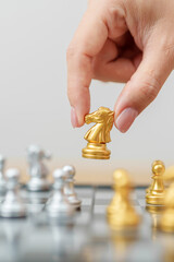 hand moving gold Chess knight figure and Checkmate opponent during chessboard competition. Strategy, Success, management, business planning, win, disruption, Trade war and leadership concept © Jo Panuwat D