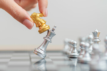 hand moving gold Chess knight figure and Checkmate opponent during chessboard competition. Strategy, Success, management, business planning, win, disruption, Trade war and leadership concept © Jo Panuwat D