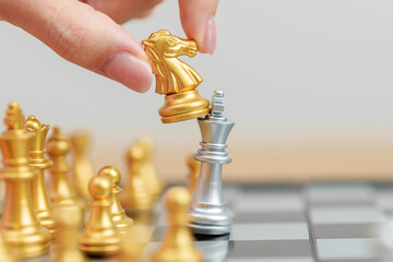 hand moving gold Chess knight figure and Checkmate opponent during chessboard competition. Strategy, Success, management, business planning, win, disruption, Trade war and leadership concept © Jo Panuwat D