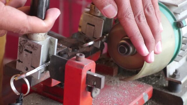 Locksmith in workshop makes new key. Professional key making in locksmith. Person who makes and repairs keys and locks. Key maker Machine and Accessory.