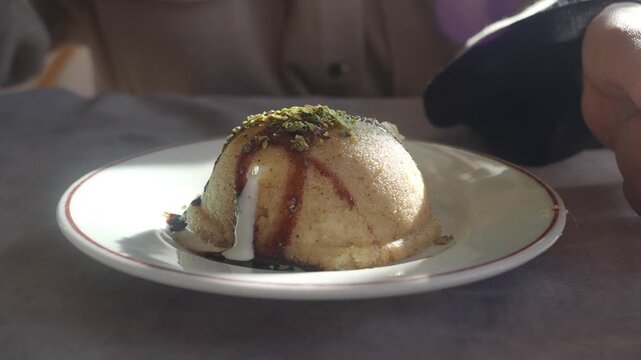 Eating delicious semolina halva dessert with ice cream and pistachios