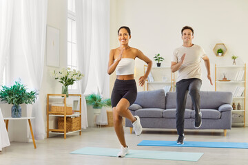 Obraz premium Couple family fitness workout at home exercise. They do high-knee cardio on mats, smiling in sync, building strength and endurance with supportive training. Motivation and health with teamwork.