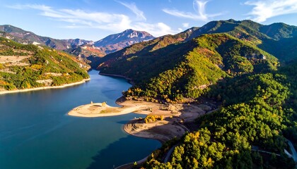Naklejka premium Aerial view of a large body of water surrounded by lush mountains and vibrant foliage