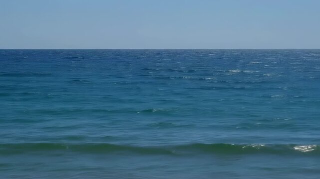 Serene ocean waves gently lap against the shore on a calm day at the beach, capturing the soothing atmosphere