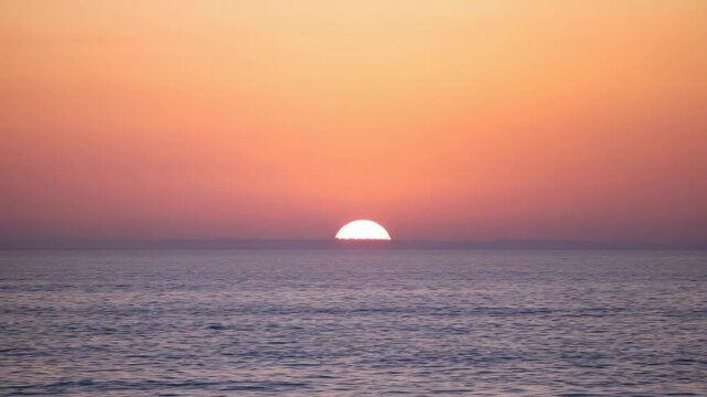 Sunset ocean horizon warm orange sky over calm sea water with peaceful tranquil mood