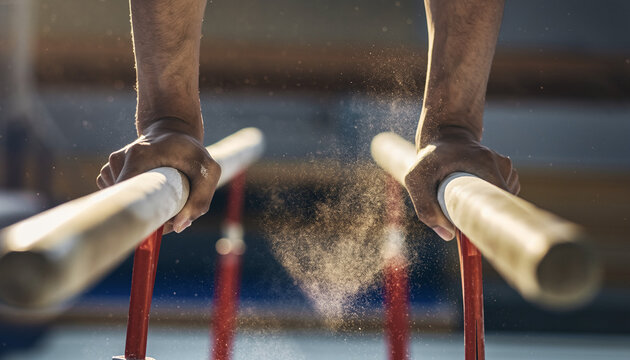 Dynamic close-up of gymnast's hands with chalk dust rising from parallel bars during practice