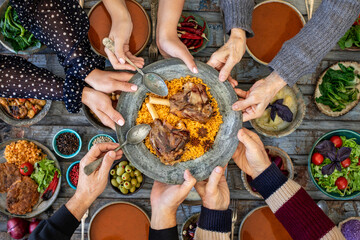 Iftar, break the fasting at holy Ramadan with family, top view of a dining table at iftar time when many human hands sharing their meal. 