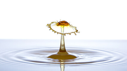 A close-up view of a water droplet creating ripples in a pool of liquid with a splash of color