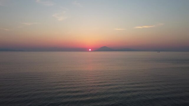 Sunset drone flight over Ionian Sea near Kyllini Greece, aerial view towards Zakynthos and Kefalonia, calm sea, golden hour sky, summer travel background, cinematic aerial video