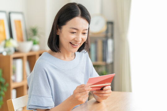 リビングで貯金通帳を見るミドルの女性