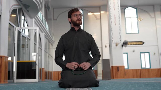 Muslims in Ramadan. Muslim man sitting alone in a mosque with prayer beads. Young Muslim scholar meditating and reciting Dhikr with rosary. Spiritual reflection and Islamic worship at masjid.