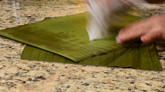 Cleaning hallaca leaves on a kitchen counter, preparing for cooking