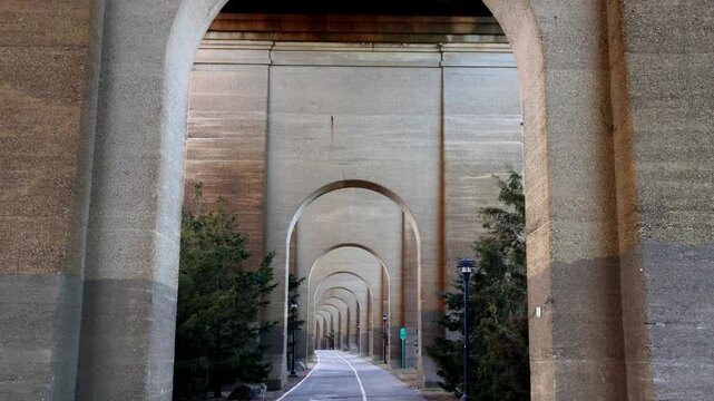 view of bike lane under stone railway bridge trestle in randall's island queens new york city (hell's gate arches brick archway public park) pedestrian cycling path nyc biking scenic infrastructure