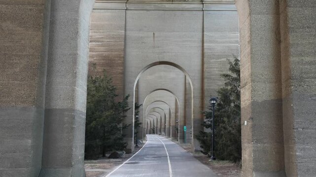view of bike lane under stone railway bridge trestle in randall's island queens new york city (hell's gate arches brick archway public park) pedestrian cycling path nyc biking scenic infrastructure