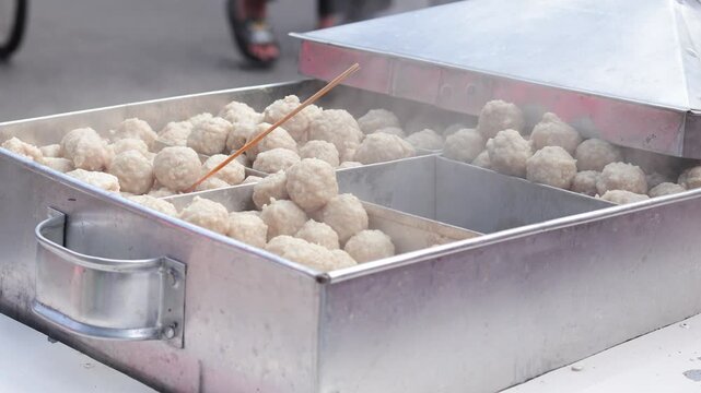 Indonesian street food meatballs steaming in a metal container with natural light