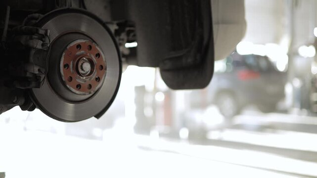 Car repair process, wheel alignment and brake inspection in action.