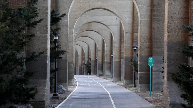 view of bike lane under stone railway bridge trestle in randall's island queens new york city (hell's gate arches brick archway public park) pedestrian cycling path nyc biking scenic infrastructure
