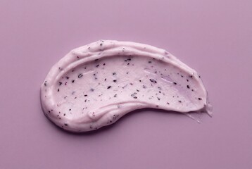 Fototapeta premium Texture of pale purple cosmetic cream with black seeds on a lilac surface