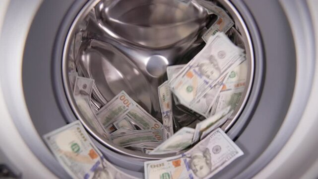 banknotes of fiat currency are spinning inside a washing machine in slow motion. Money laundering and fraud theme.