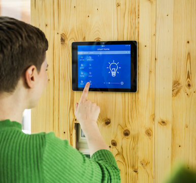 Woman using smart home touch screen tablet to control lighting