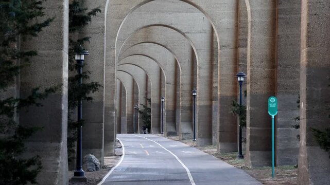 view of bike lane under stone railway bridge trestle in randall's island queens new york city (hell's gate arches brick archway public park) pedestrian cycling path nyc biking scenic infrastructure