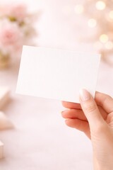 Obraz premium Blank White Card in Female Hand on Soft Pink Background