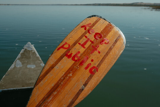 Wooden canoe paddle reading keep it public on summer lake