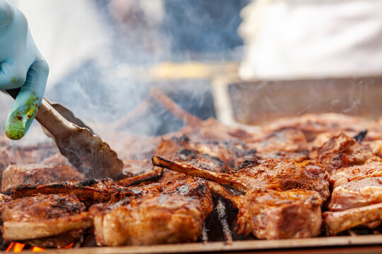 Rack of seasoned lamb cooking on smokey grill