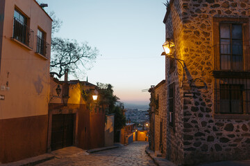 Naklejka premium San miguel de allende cobblestone street at dusk glowing lanterns