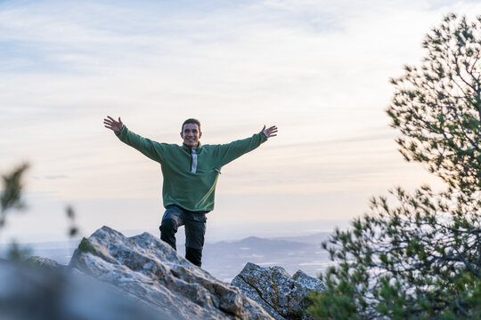 Man with arms wide celebrating success on mountain peak