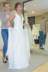 Naklejka premium skillful designer fitting bridal gown to girl
