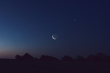 Fototapeta premium Morning old Moon with stars, planets and rural countryside tree silhouettes.