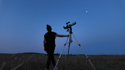 Fototapeta premium Amateur astronomer using telescope for watching stars, Moon, planets and other celestial objects from a field in nature.