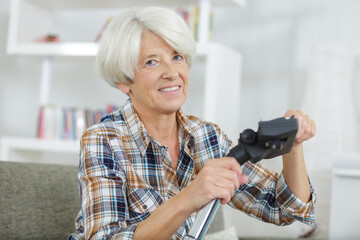 senior woman looking at camere before vacuuming carpet at home