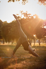 Woman practicing yoga and stretching in the park on a hot sunny summertime day.