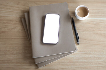 wooden table with notebooks and phone with clean white display. work from home concept. home office aesthetic. working, learning, studying