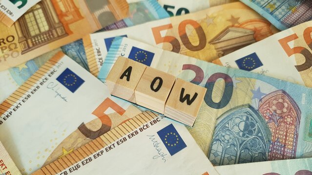 AOW acronym made of wooden letter cubes on pile of Euro banknotes. Algemene Ouderdomswet (General Old Age Pensions Act)