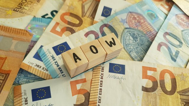 AOW acronym made of wooden letter cubes on pile of Euro banknotes. Algemene Ouderdomswet (General Old Age Pensions Act)