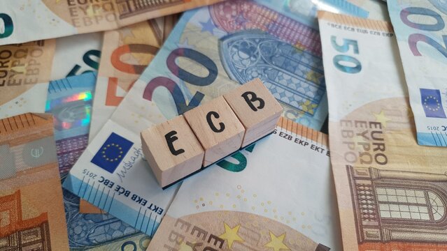 ECB acronym made of wooden letter cubes on pile of Euro banknotes. European Central Bank