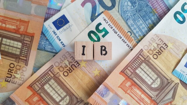 IB acronym made of wooden letter cubes on pile of Euro banknotes. Inkomstenbelasting (Income Tax)