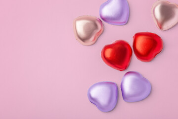 Fototapeta premium Heart chocolate with colorful foil wrapped on pink background, valentines day and love concept, top view