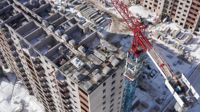 Aerial drone footage of an unfinished high-rise construction site in an urban area. Large residential building under development