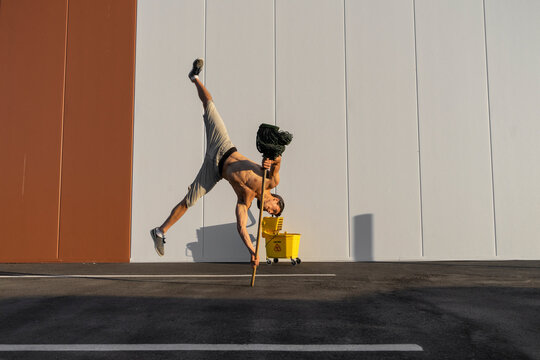 Acrobat playing with cleaning bucket and mop