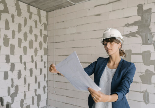 Female architect checking architectural plan on construction site