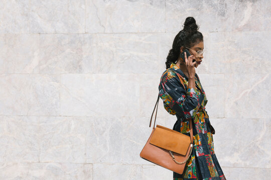 Portrait of chic woman wearing patterned dress talking on cell phone