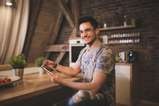 Portrait of smiling young man using tablet in kitchen at home